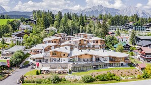 A modern resort with multiple chalet-style buildings, outdoor seating areas, and a view of mountains in the background. - AlpenParks Chalet & Apartment Alpina Seefeld (Seefeld in Tirol)