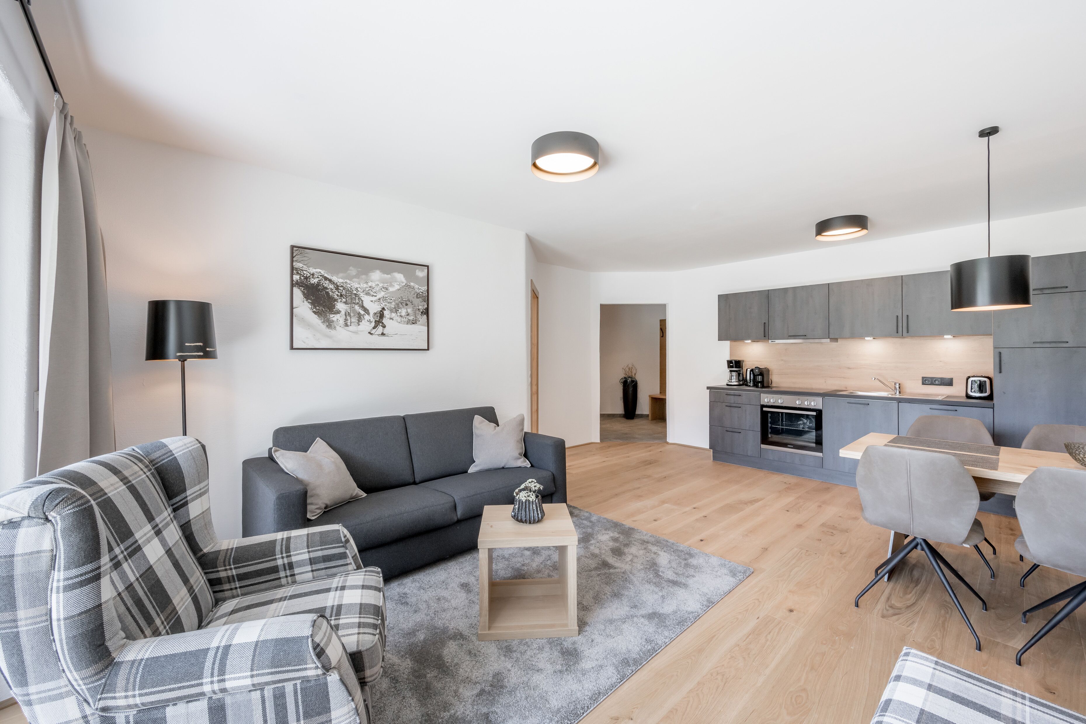Un salon moderne comprenant un canapé, une table basse et un coin repas avec des chaises.