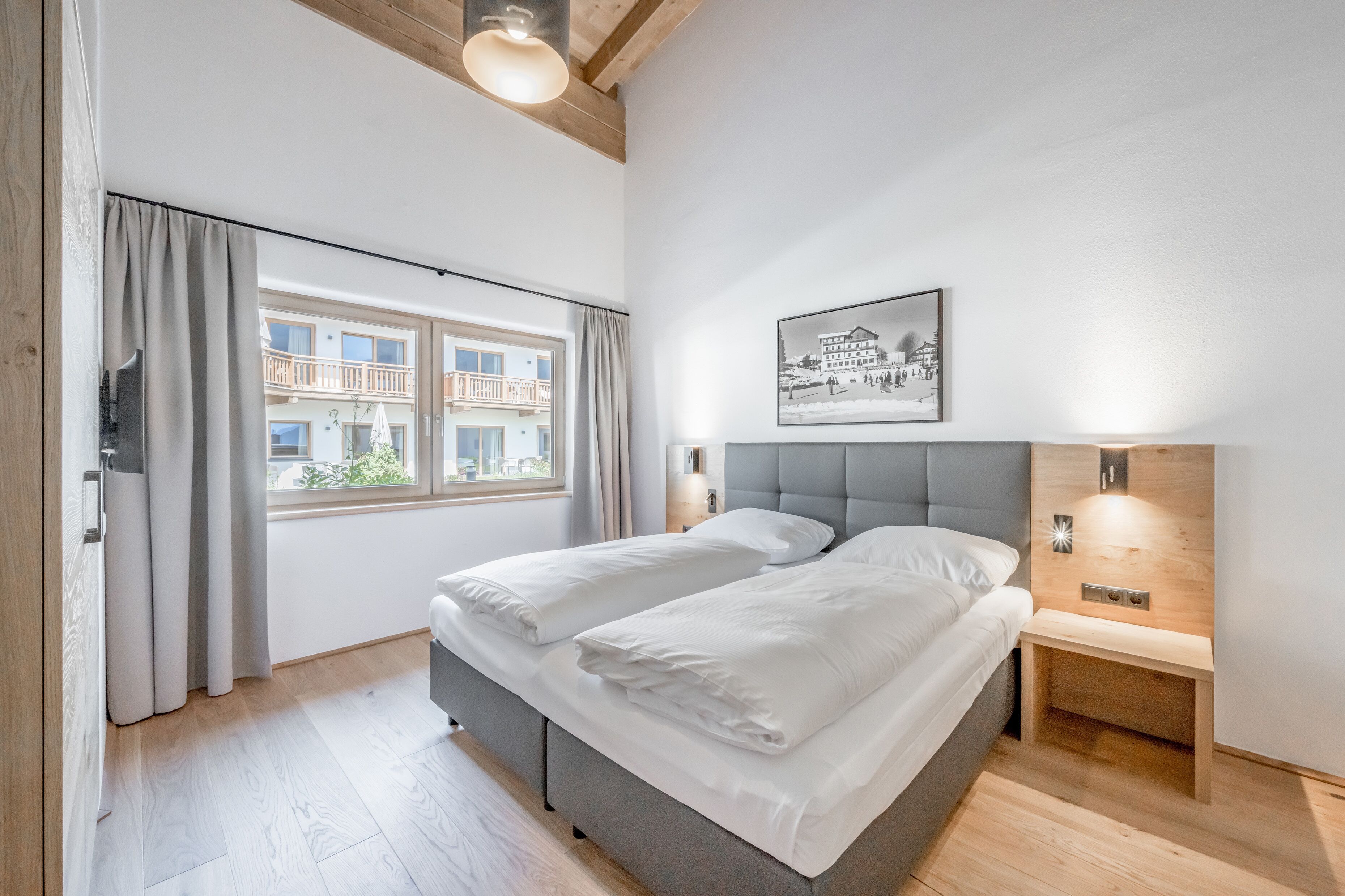 A modern bedroom with a bed, bedside tables, and a window with curtains.