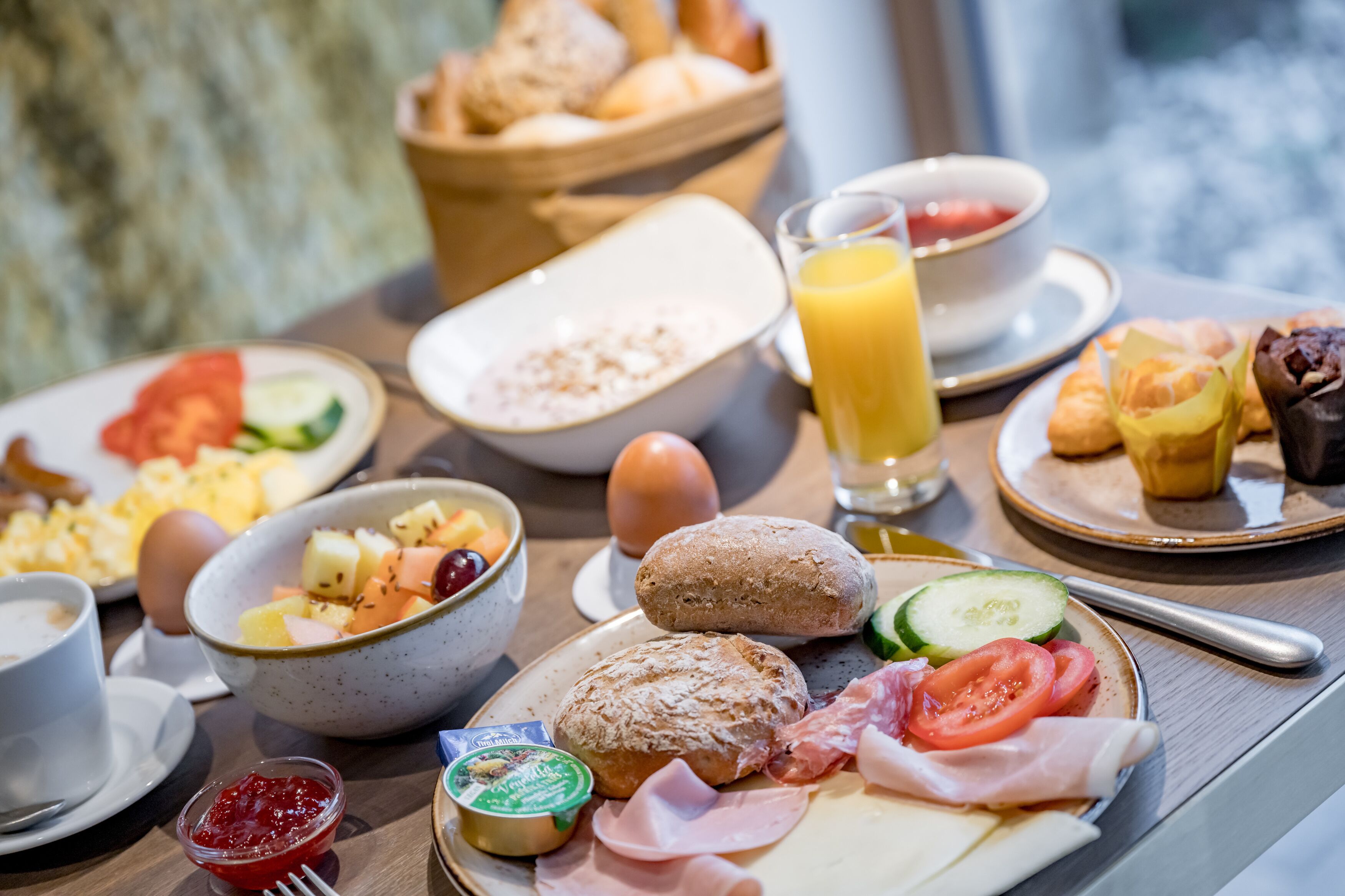 A breakfast buffet with various dishes including eggs, bread, fruits, and meats.