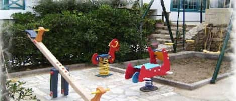 A playground with various play equipment including a seesaw, a swing set, and a climbing structure.