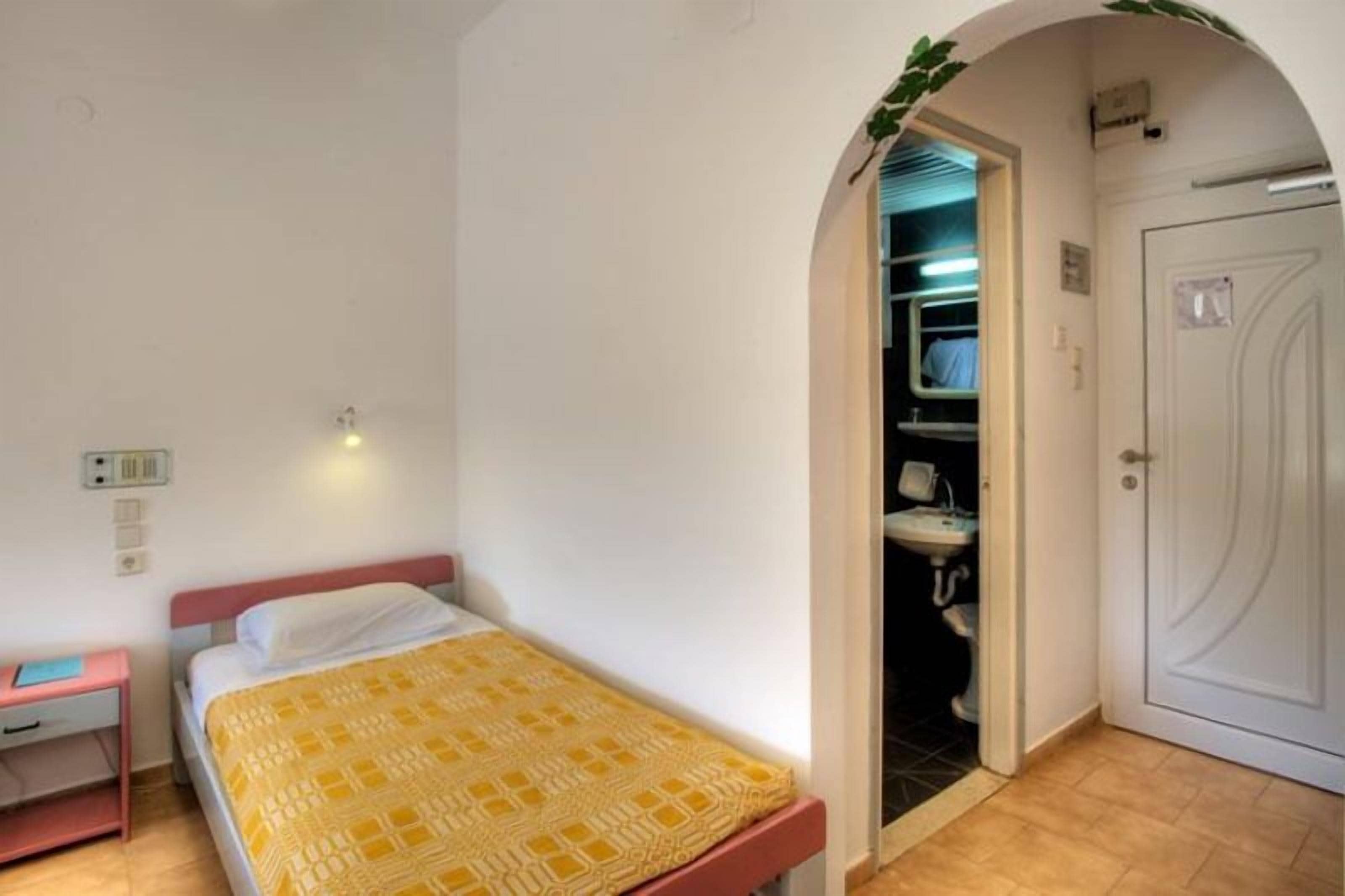 Een slaapkamer met een bed, nachtkastje, kledingkast, en een open deur naar een badkamer.