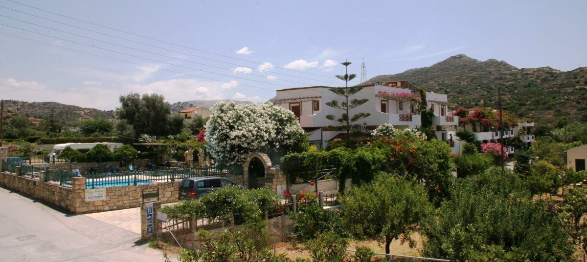 A residential area with a swimming pool, stone walls, and houses with balconies.