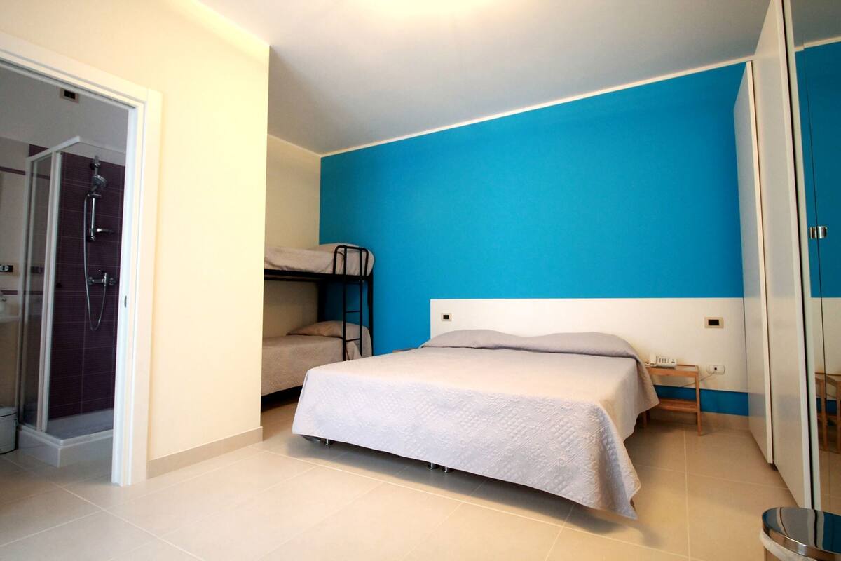 A bedroom with a bed, a chair, a small table, and a wardrobe.