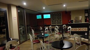 A restaurant with multiple tables and chairs, a counter, and two televisions on the wall. - B&B Le Parmente (Casarano)
