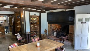 A rustic interior with a wooden table, chairs, a fireplace, and a sign indicating a lounge area. - The George & Dragon Country Pub & Hotel (Tadley)