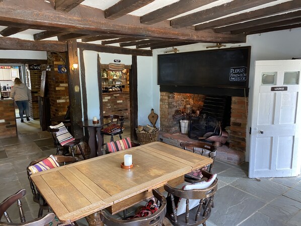 Un intérieur rustique avec une table en bois, des chaises, une cheminée et un panneau indiquant un espace détente.