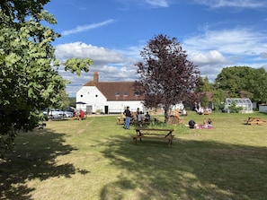 A white building with a large lawn, picnic tables, and a tree in the center. - The George & Dragon Country Pub & Hotel (Tadley)