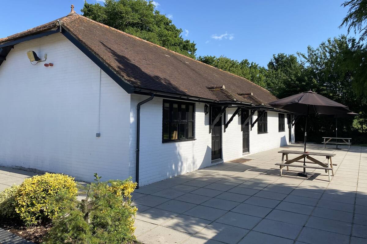 A white building with a tiled patio, a black awning, and a wooden bench.