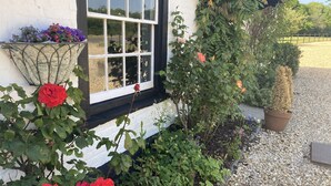 A building with a white exterior, a window with multiple panes, and a gravel pathway leading to a wooden fence. - The George & Dragon Country Pub & Hotel (Tadley)