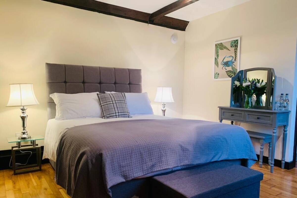 A bedroom with a bed, bedside lamps, a dresser, and a mirror.