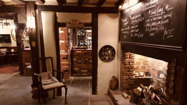 A cozy pub interior with a brick fireplace, wooden furniture, and a chalkboard menu. - The George & Dragon Country Pub & Hotel (Tadley)