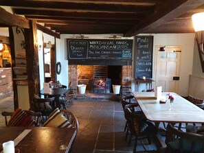 A restaurant interior with a brick fireplace, wooden beams, and a chalkboard menu. - The George & Dragon Country Pub & Hotel (Tadley)