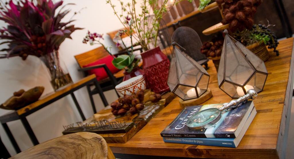 Uma mesa de madeira decorada com objetos como livros, um vaso e um candeeiro.