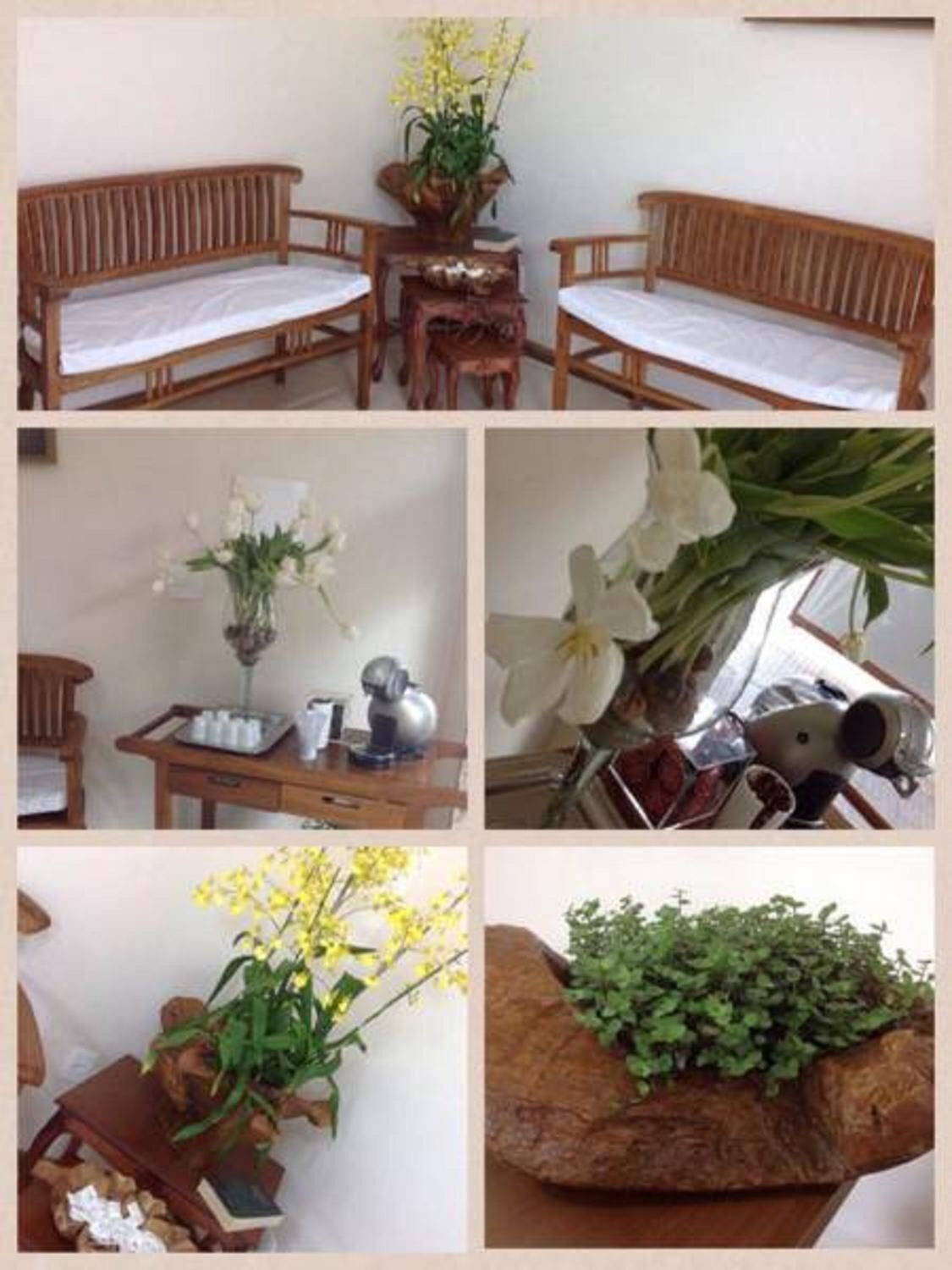 A room with a wooden bench, a small table with a vase of flowers, and a rock with greenery.