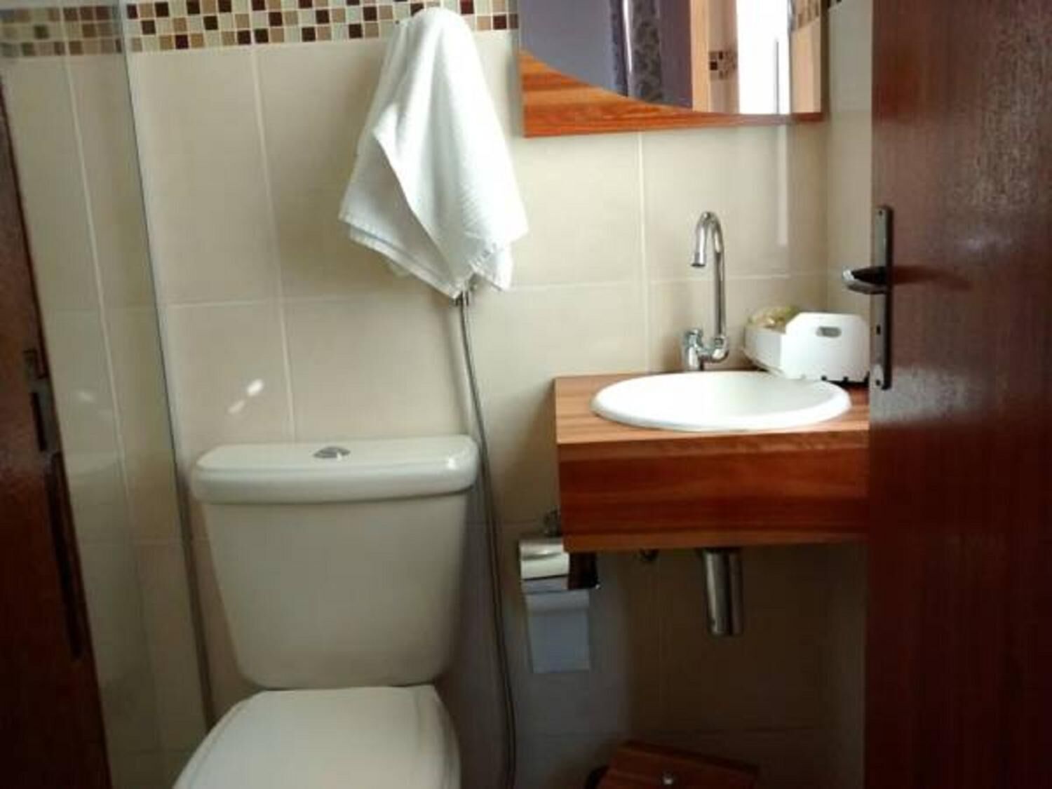Une petite salle de bain avec des toilettes, un lavabo et un miroir.