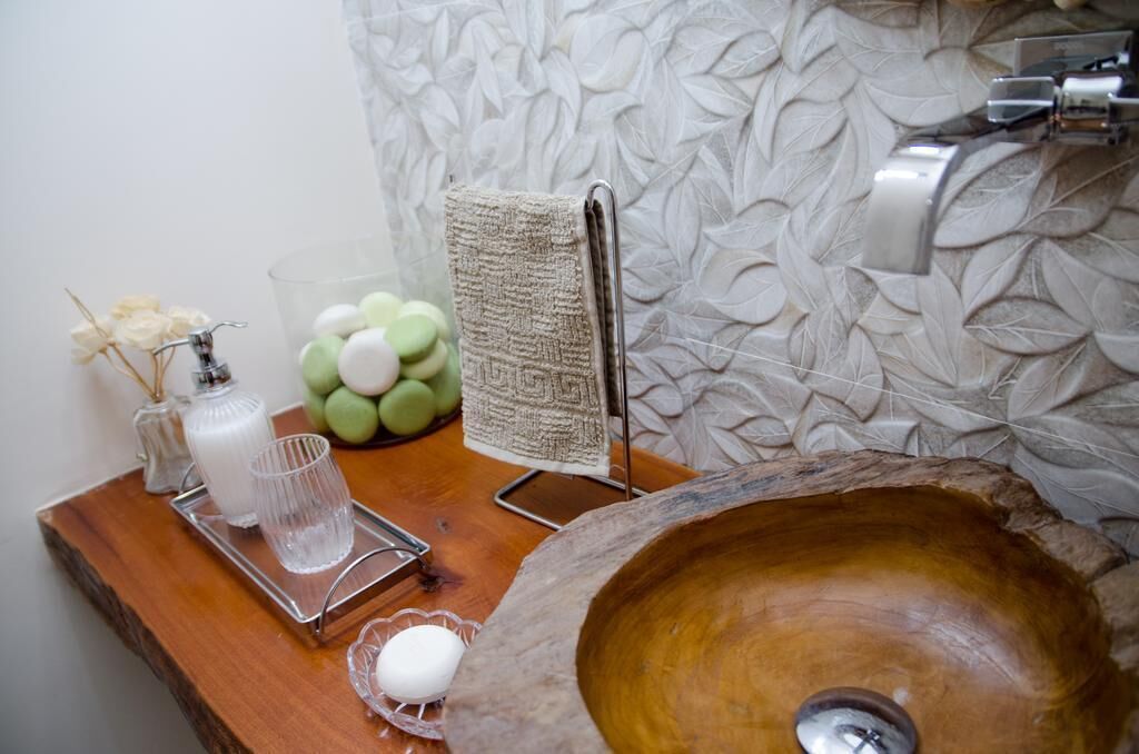 A wooden sink with a large basin, a towel rack, a glass tray with a candle, a glass, and a small vase with dried flowers.