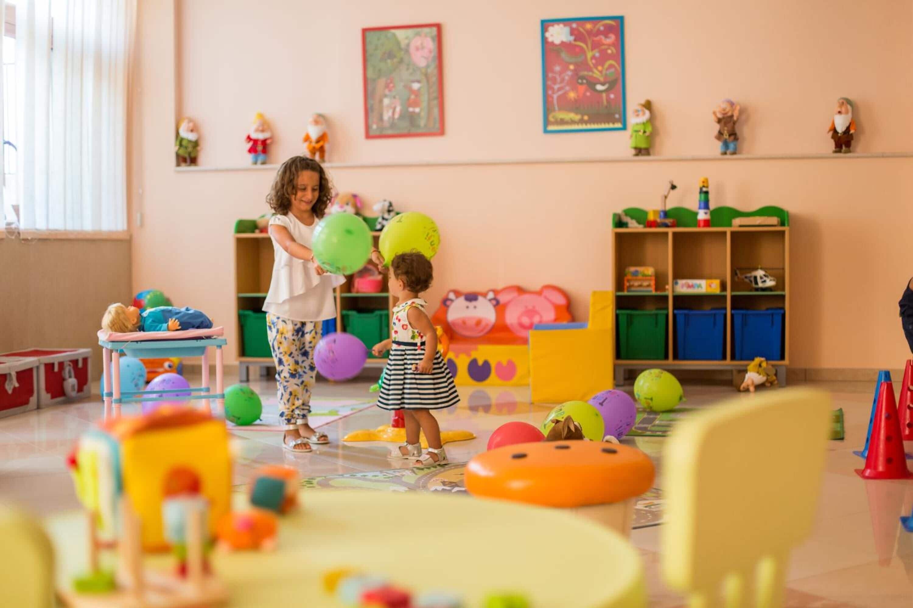 Una stanza con un'area giochi per bambini, con giocattoli e palloncini colorati.