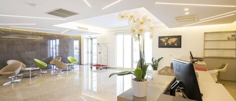 A modern reception area with a desk, chairs, and a potted orchid.