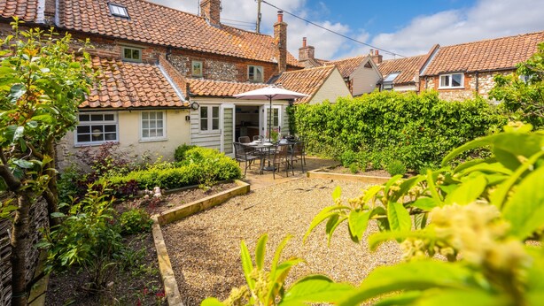 Il s’agit d’une propriété résidentielle dotée d’un patio avec jardin, de cheminées en briques et d’un toit en tuiles.