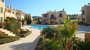 Zona residenziale con piscina circondata da giardini curati e cielo sereno.