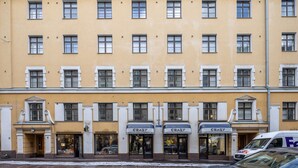 A multi-story building with a yellow facade, multiple windows, and storefronts labeled "CRAZY". - Scandinavian Apartments Fredrikinkatu (Helsinki)