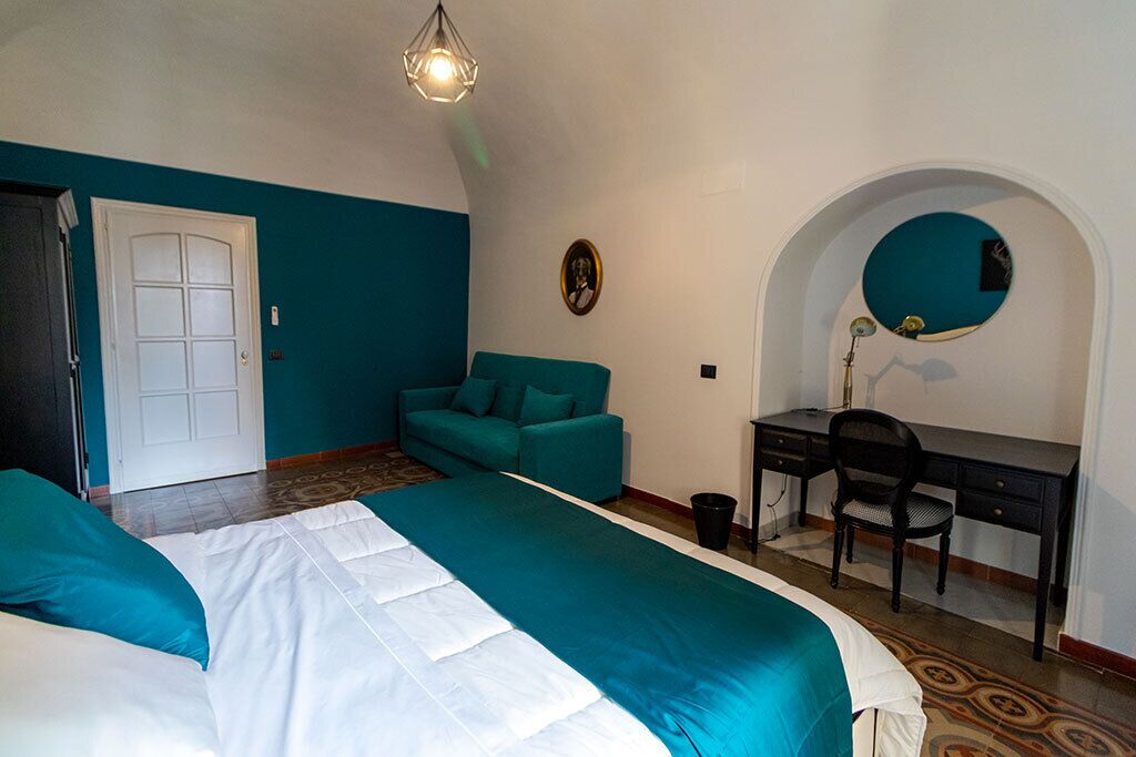 A bedroom with a bed, a desk, and a chair.