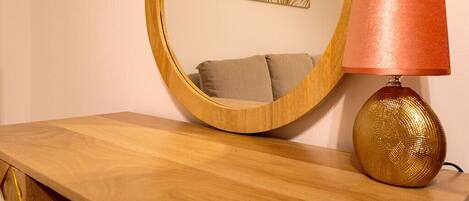 A wooden dresser with a round mirror and a lamp with a textured base.