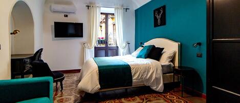 Habitación de hotel con cama, televisión, armario y alfombra estampada.