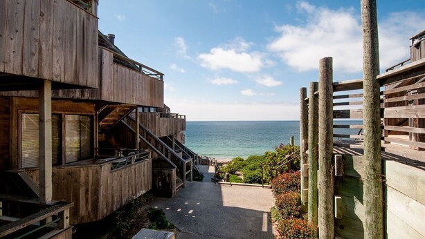 Ein hölzernes Gebäude mit einem Balkon mit Blick auf einen Strand.