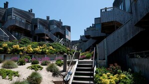 Ein modernes Gebäude mit markanter Architektur, mehreren Ebenen, Außenstufen und vielfältigen Pflanzen und Blumen.