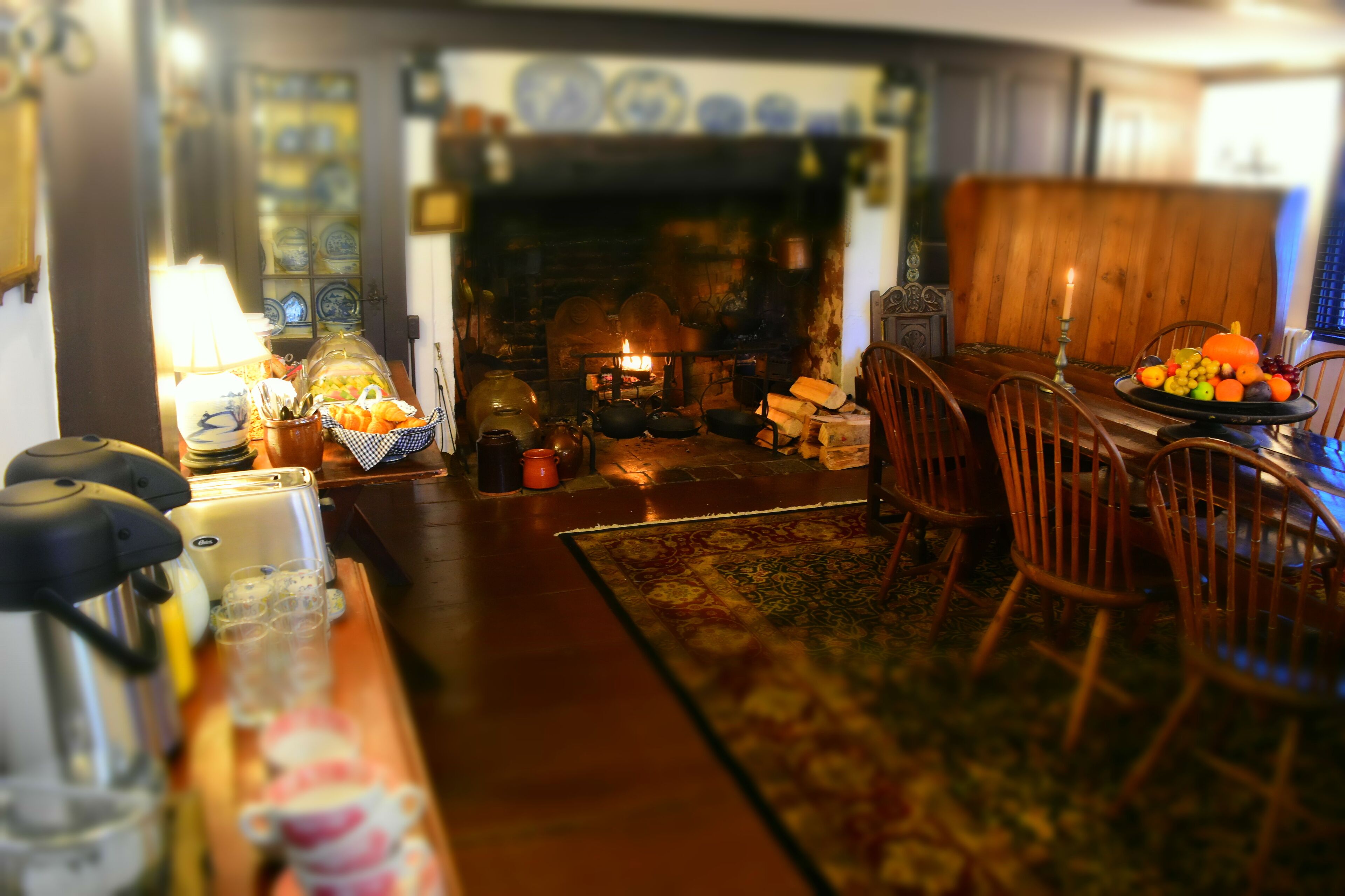 A cozy living room with a fireplace, wooden furniture, and a dining table set for a meal.