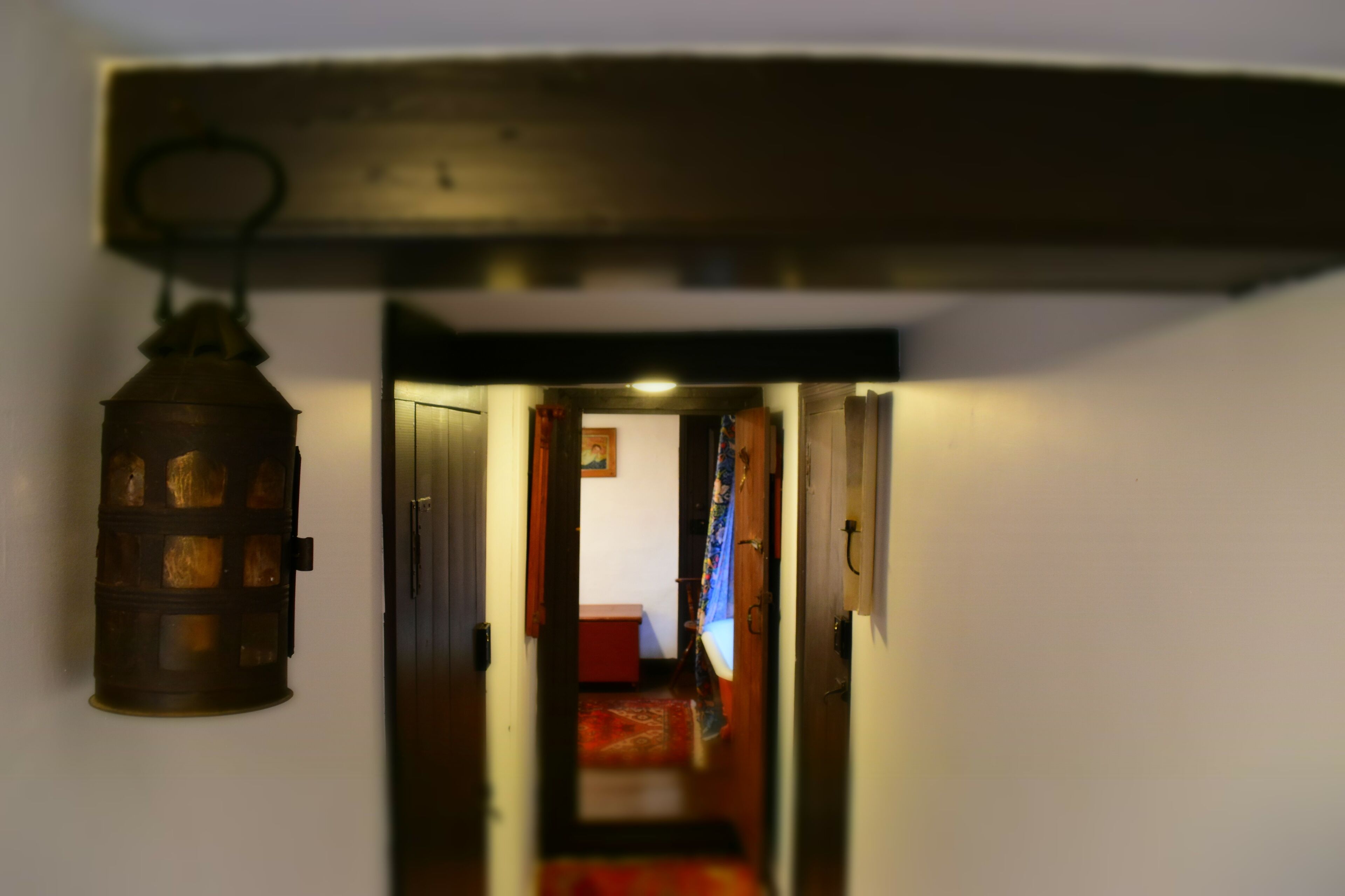 A narrow hallway with a hanging lantern and a wooden door frame.