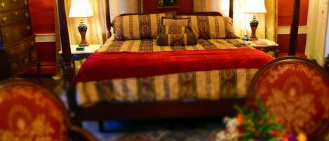 A hotel room with a large bed, two bedside tables with lamps, a dresser, and a floral arrangement.