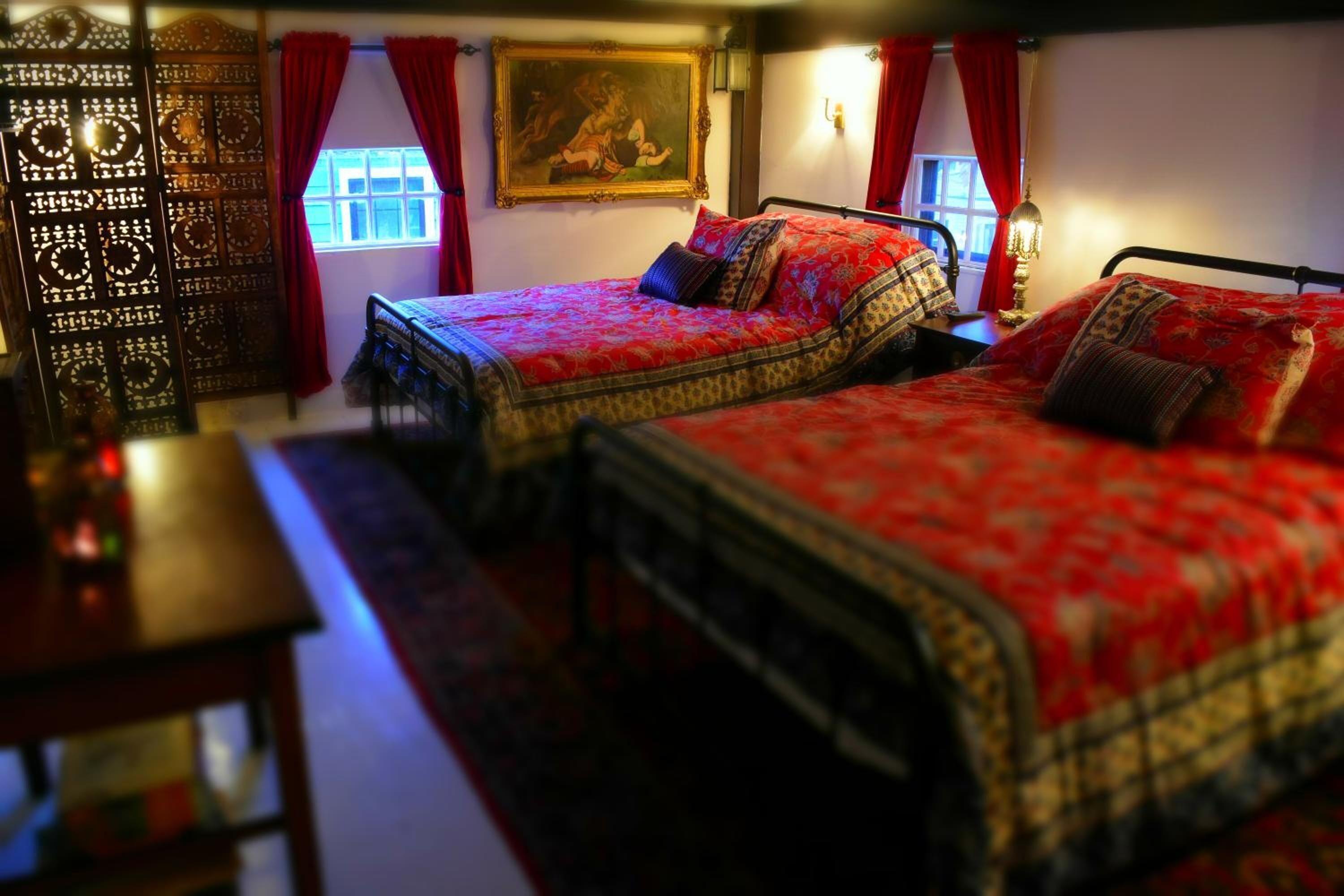 Een kamer met twee bedden, een houten tafel en een decoratieresistent scherm.