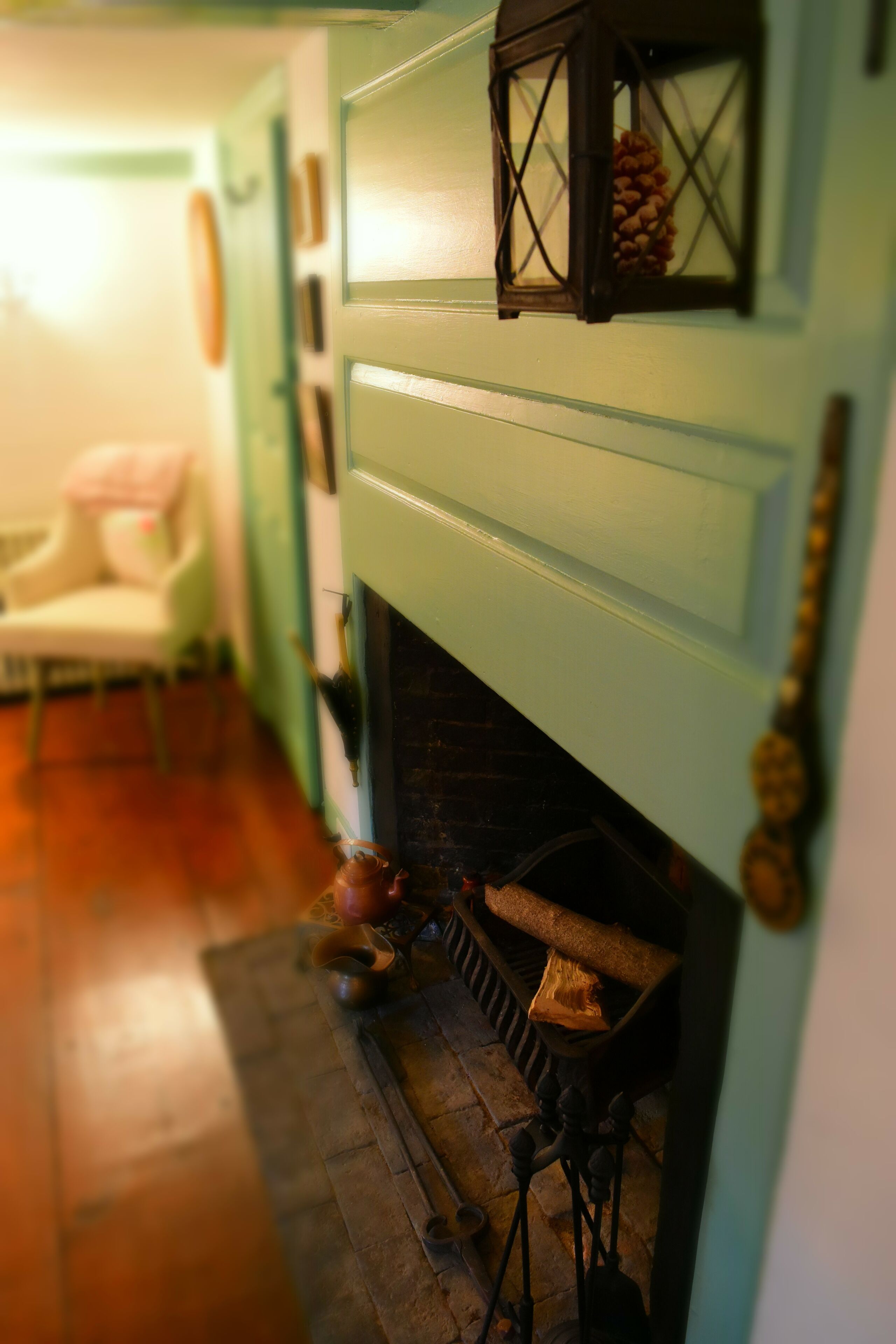 Une pièce avec une cheminée, un fauteuil et un plancher en bois.