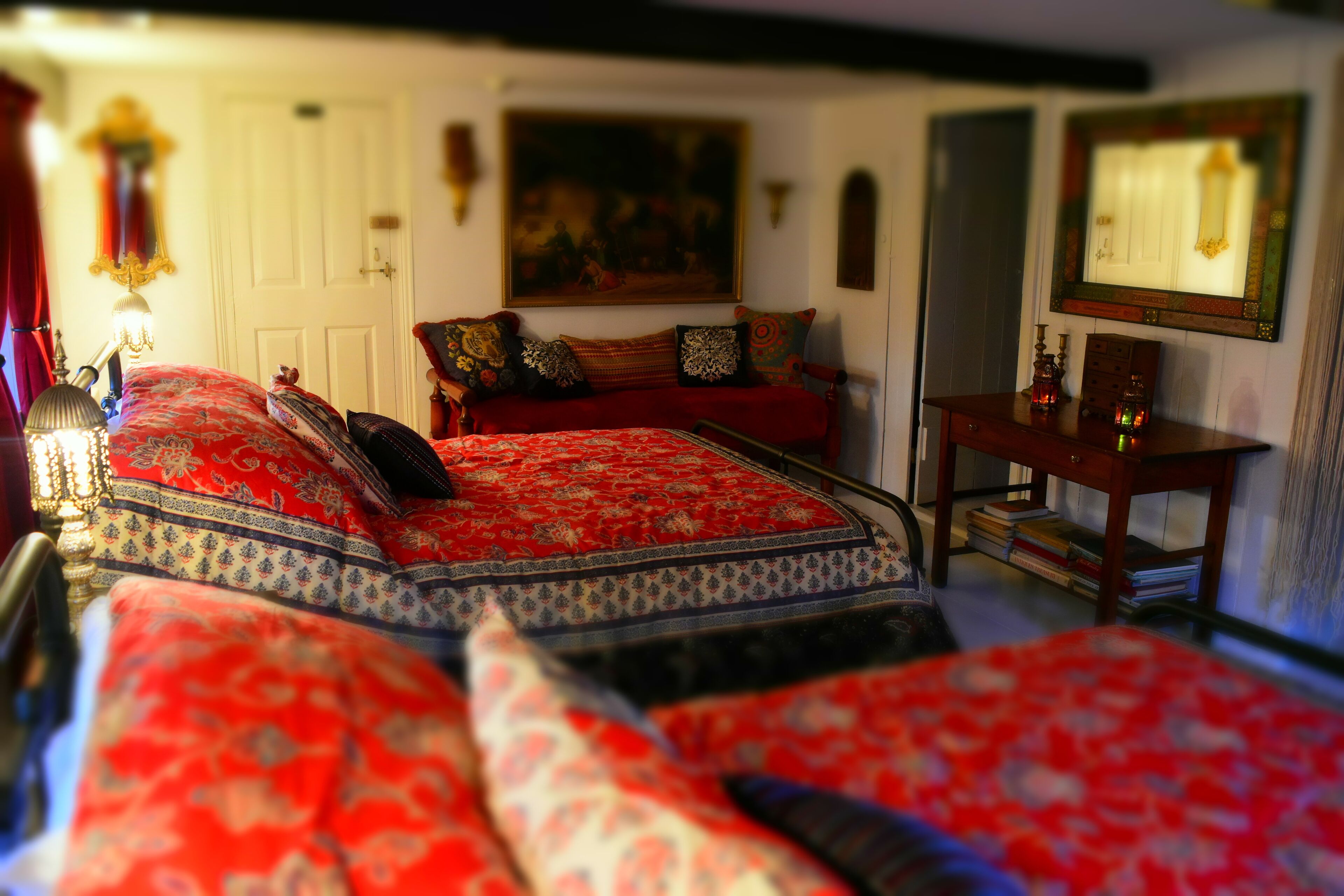 Ein Schlafzimmer mit einem großen Bett, einem Holznachttisch, einem Schreibtisch und einem Gemälde an der Wand.