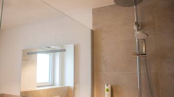 A modern bathroom with a glass shower enclosure, a large mirror, and a handheld showerhead.