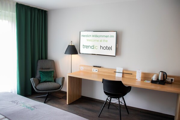 Una habitación de hotel moderna con un escritorio de madera, dos sillas, una lámpara y un cartel dando la bienvenida a los huéspedes al hotel moderno.