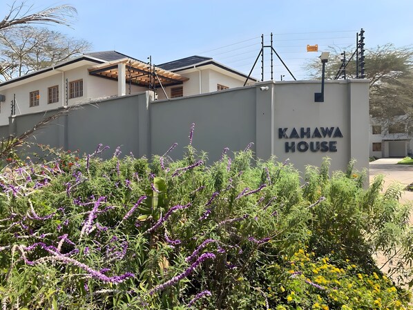 A building with a sign reading "KAHAWA HOUSE" surrounded by dense vegetation and a clear sky. - Kahawa House (Arusha)