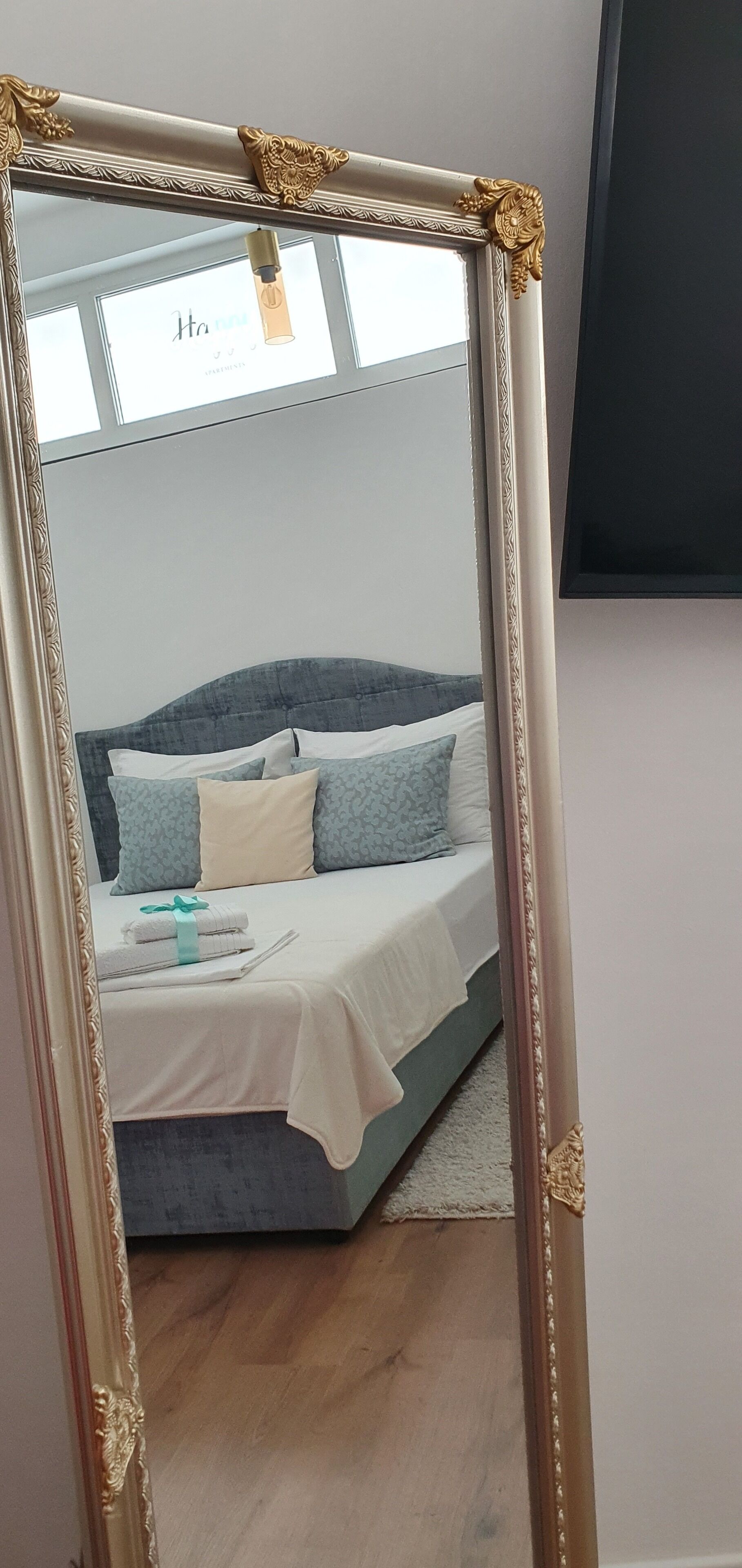Une chambre à coucher avec un lit, des oreillers, une table de chevet et un miroir.