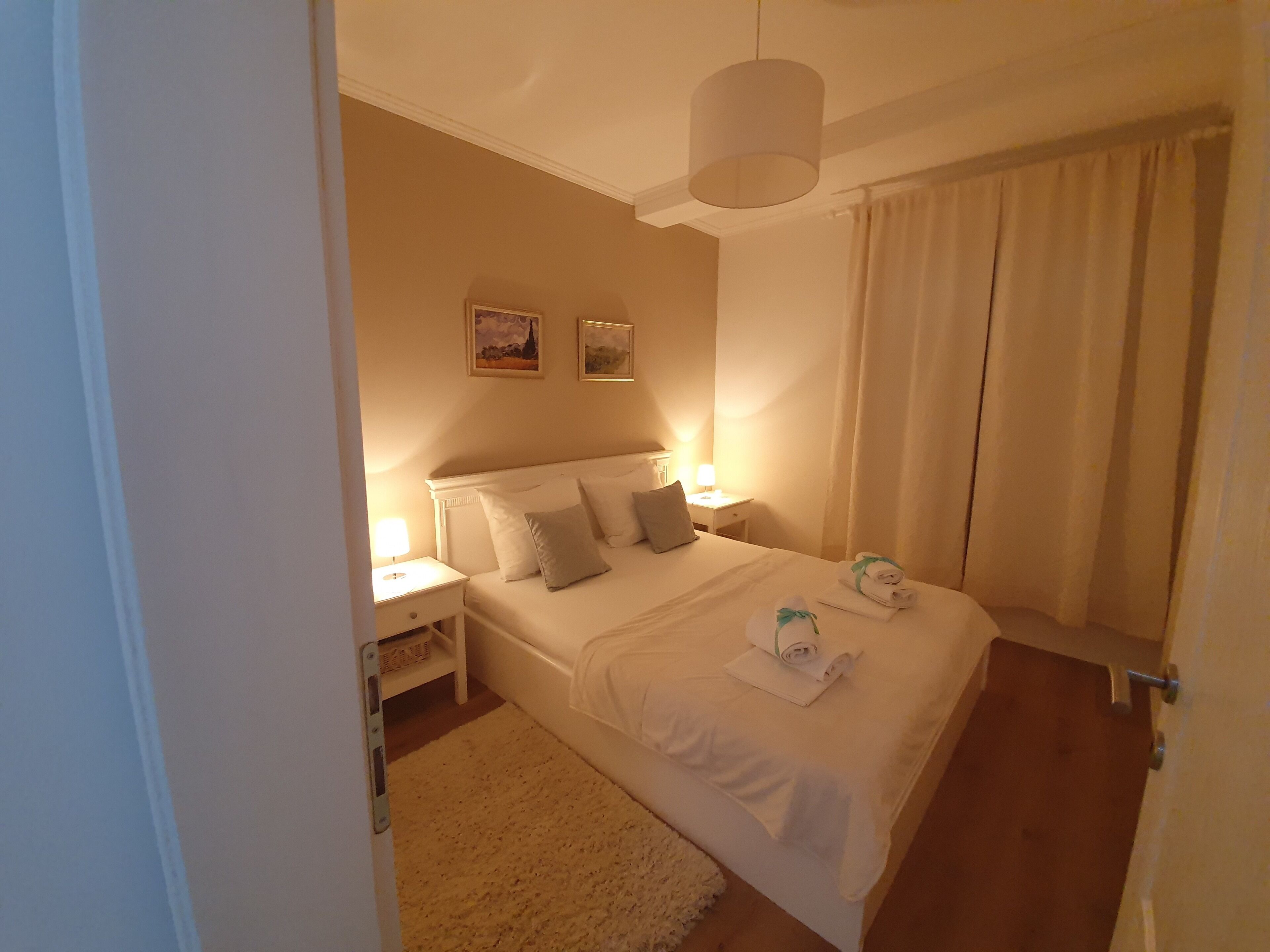 Ein Hotelzimmer mit einem großen Bett, einem Nachttisch, einer Lampe und einem Gemälde an der Wand.