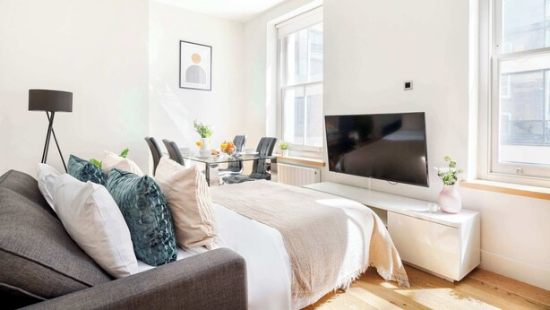 A modern bedroom with a bed, a TV, a desk, and a chair. - Fitzrovia Lovely 1BR Flat (London)