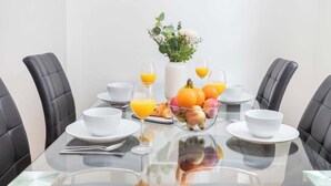 A breakfast table set with bowls, glasses, and a fruit bowl. - Fitzrovia Lovely 1BR Flat (London)
