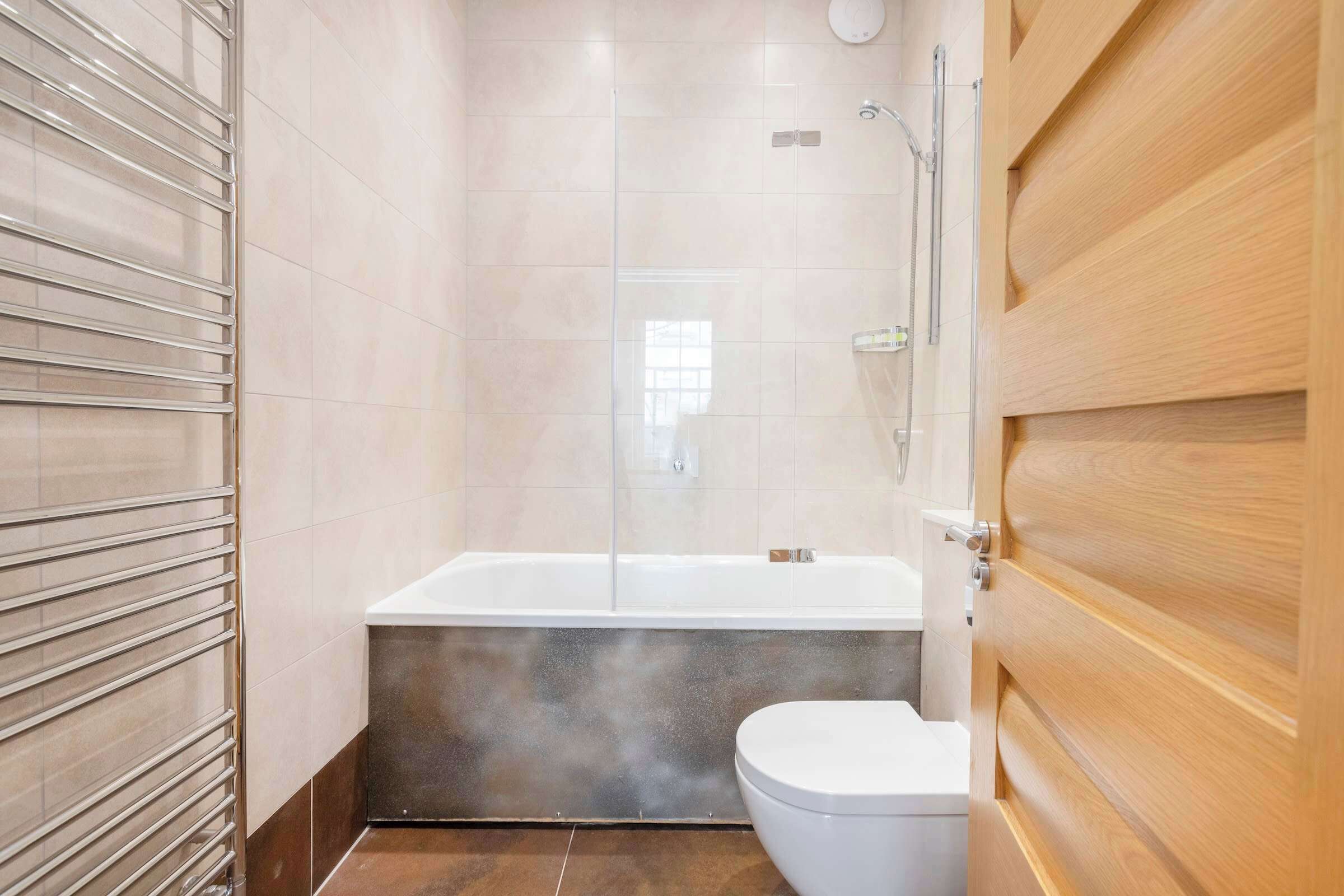 Un baño moderno con ducha envuelta en vidrio, bañera blanca y un inodoro.