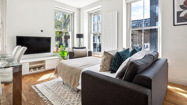 Un dormitorio moderno con una cama grande, un televisor y una zona de estar con sofá y sillones.
