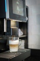 Una máquina de café sirviendo café en una taza de vidrio.