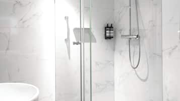 A modern bathroom with a glass-enclosed shower, a white sink, and a toilet.