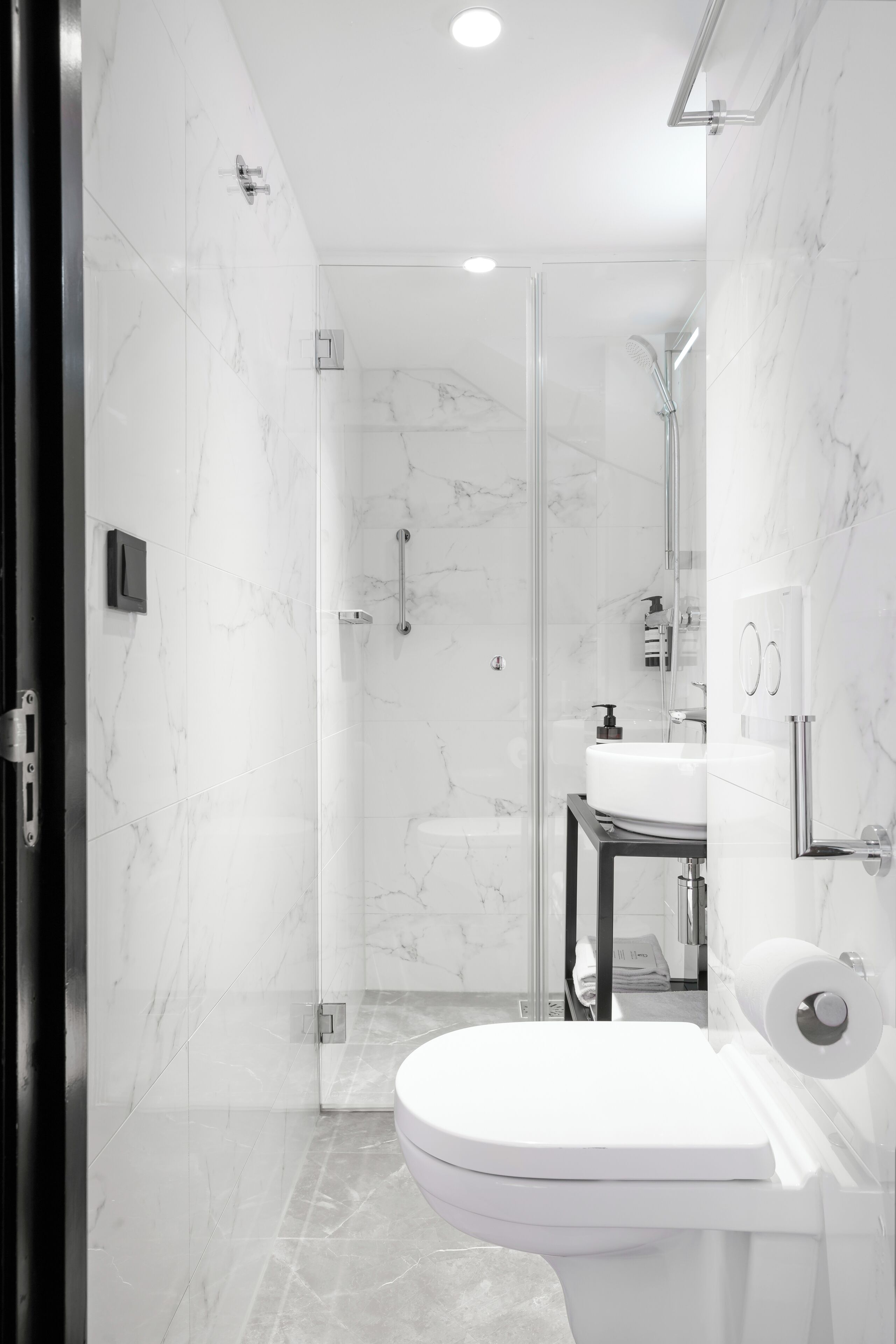 A modern bathroom with a glass shower enclosure, a white toilet, and a sink with a mirror.