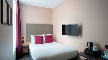 A hotel room with a bed, a TV, a desk with a phone, and a coffee maker.